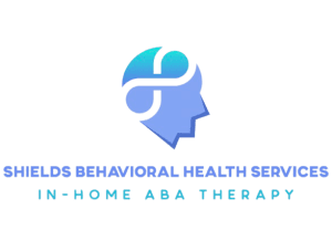 A blue logo with a stylized human head and shield, with the text “SHIELDS BEHAVIORAL HEALTH SERVICES IN-HOME ABA THERAPY” below.